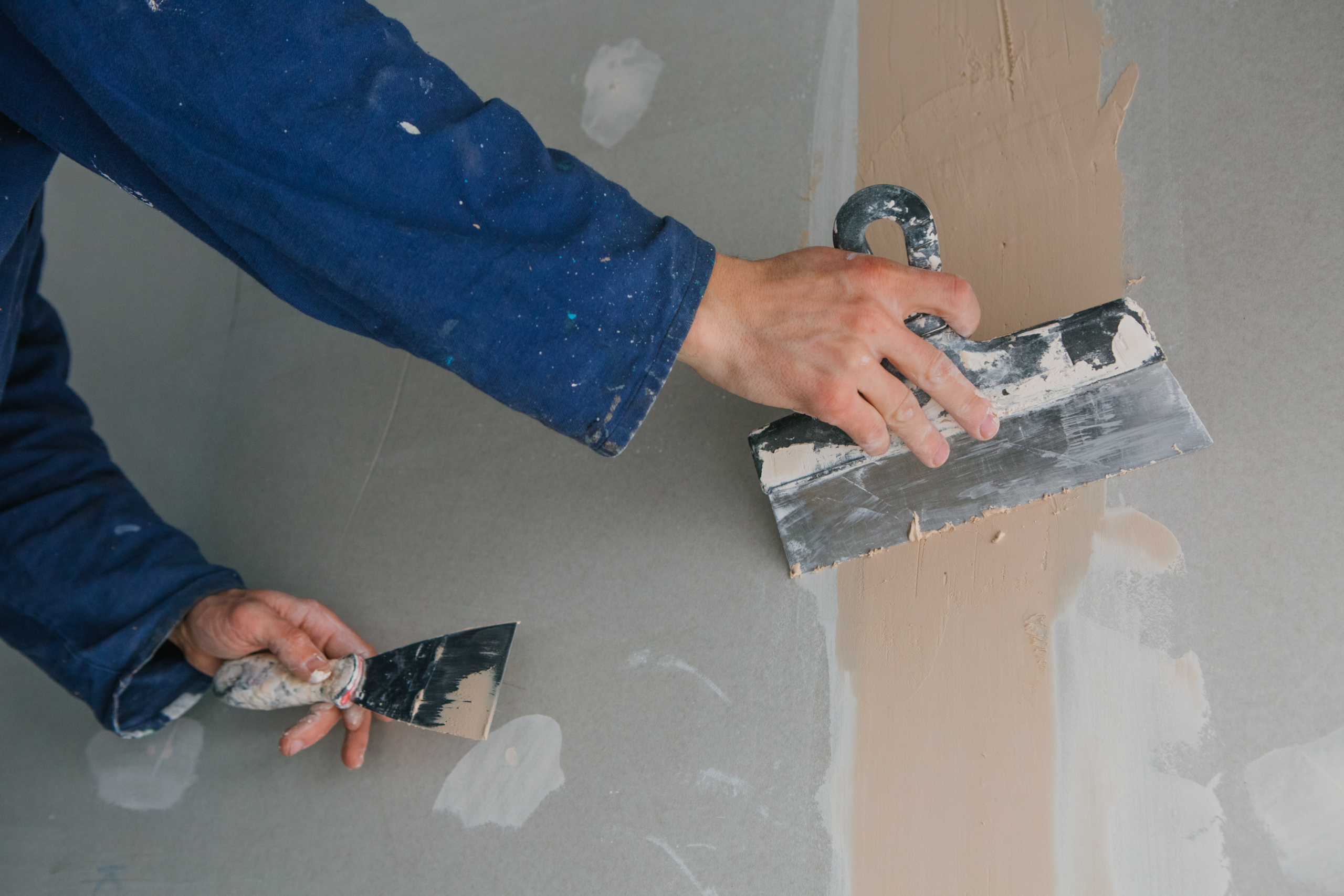 Worker plastering drywall. Drywall Repair